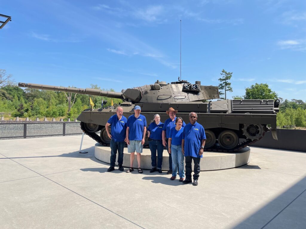 El Amigos Basis club staan voor een tank, heerlijk in de zon., de volgende personen staan erop: Bessel Van Den Hazel, Cedric Craane, Karin Plug, Linda Picaulima, Marco visser en de voorzitter Hans visser.